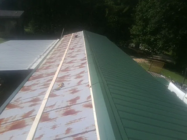 Old rusted panels beside newly installed green metal roofing — Wind Damage Roof Repair by Roofing Brothers in Hendrum