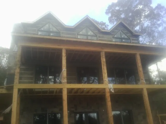 Dormers and porch framing on a large log home under construction — Roof Coating work by our crew in Hendrum