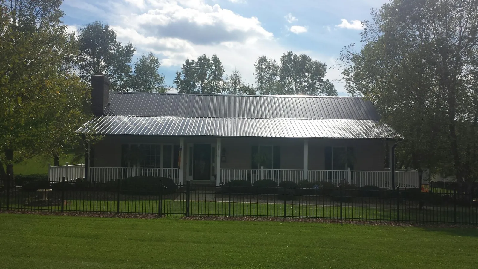 Gray metal roof on a brick ranch with a full width front porch — Gutter Guard Installation work by our crew in Hendrum