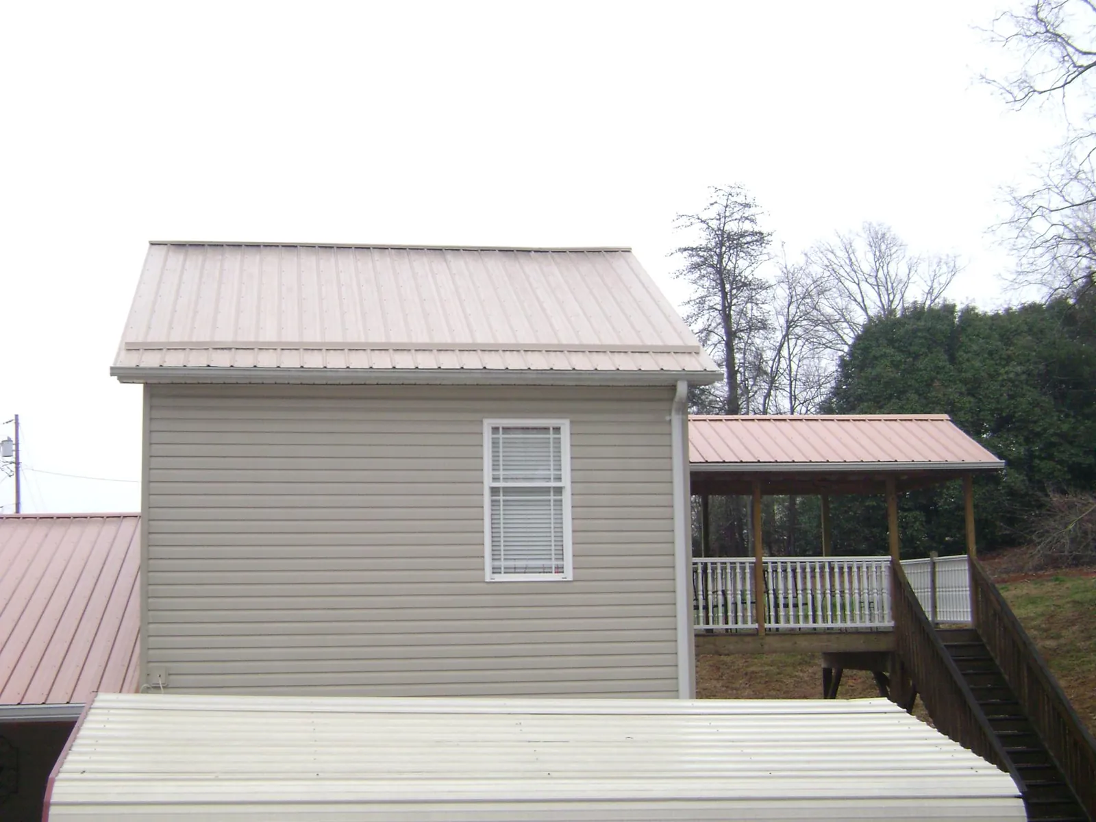 Tan metal roofs on a two story addition and attached porch, from a Roof Replacement job in Hendrum