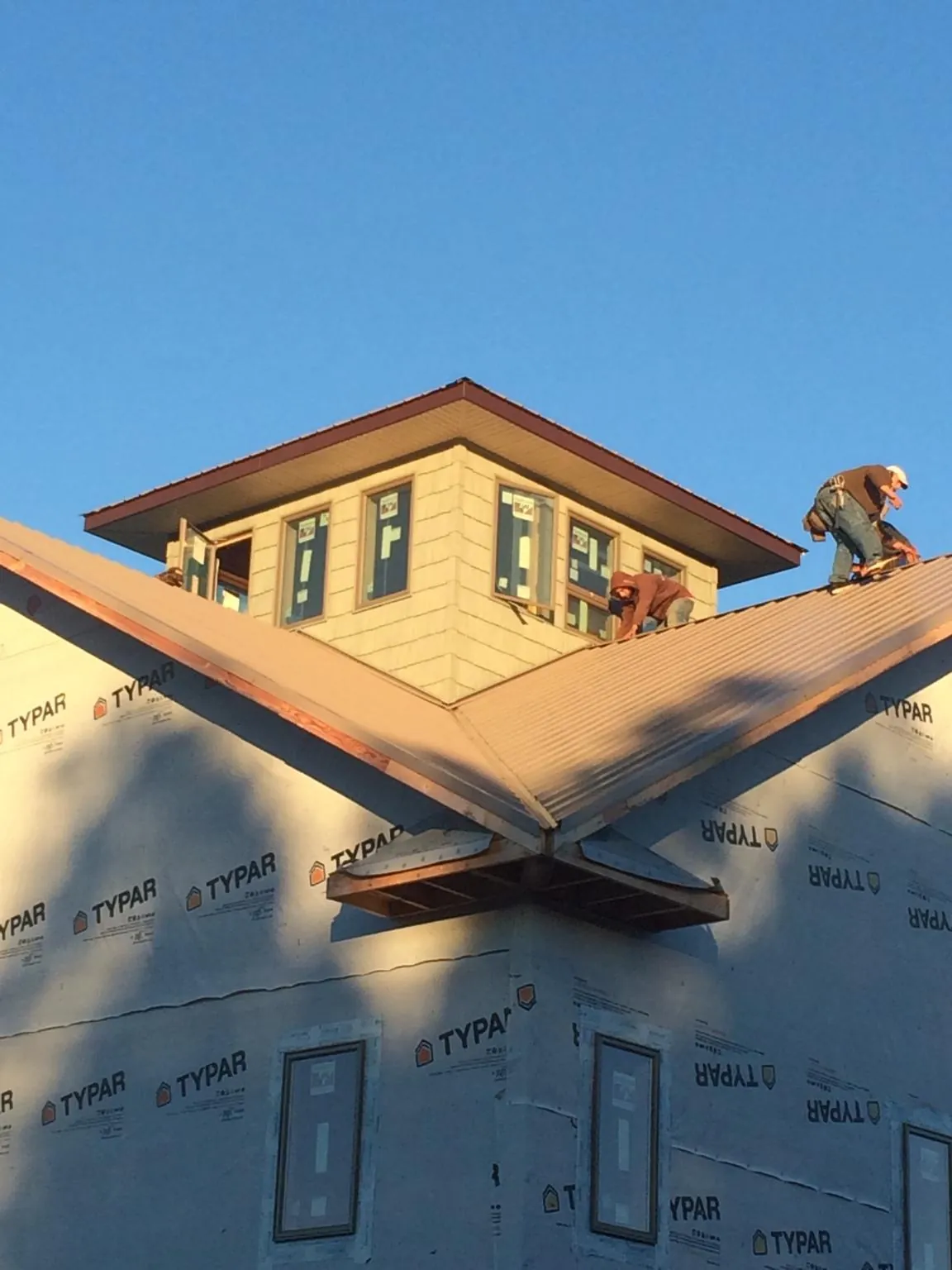 Roofers working around a rooftop cupola on a new metal roof at sunset — Roof Waterproofing in Hendrum by Roofing Brothers